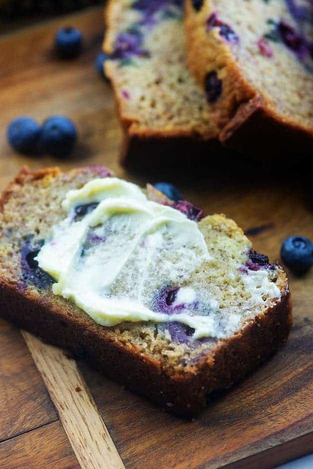 banana bread with blueberries and butter on wooden cutting board