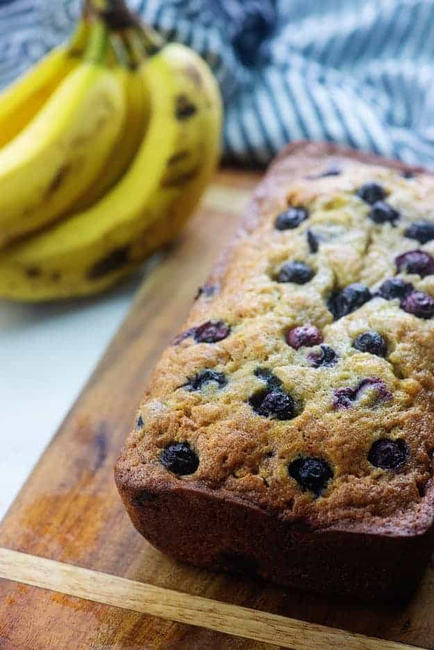 banana bread with blueberries on wooden cutting board