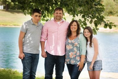 A picture of Karly, owner of buns in my oven, with her husband and two children in front of a lake.