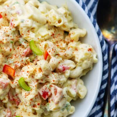 creamy amish macaroni salad in white bowl with striped napkin