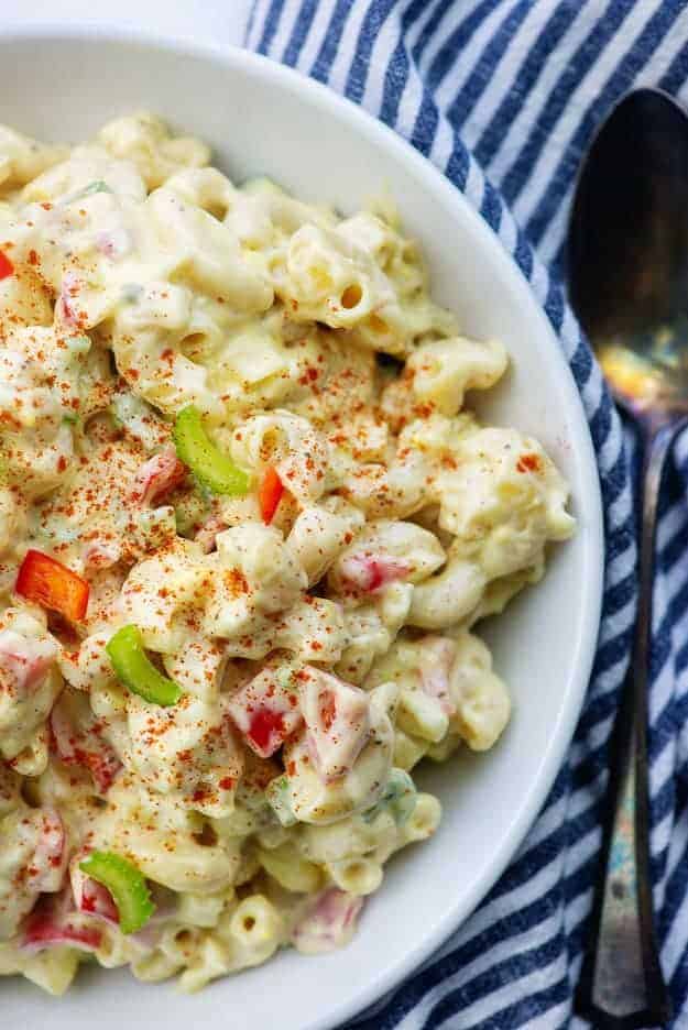 creamy amish macaroni salad in white bowl with striped napkin