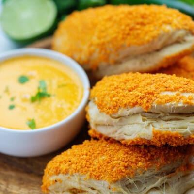 A close up of taco pockets on a cutting board with a dish of dip on the side.