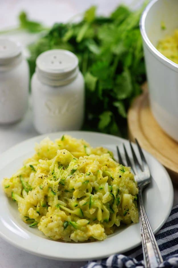 rice recipe mixed with cheese and zucchini on white plate