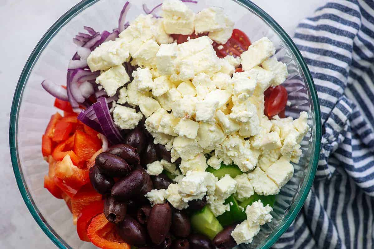 ingredients for greek pasta salad in glass bowl