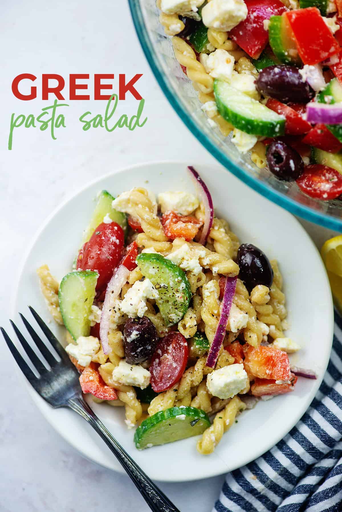 Greek pasta salad on white plate with blue striped napkin