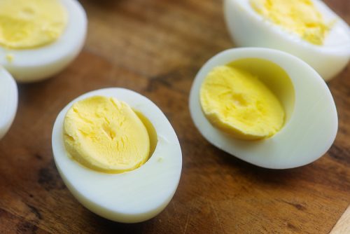 hard boiled eggs sliced in half on wooden cutting board