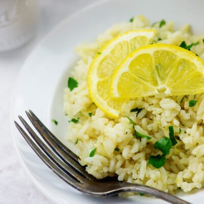 A plate of rice on a table topped with two lemon slices.