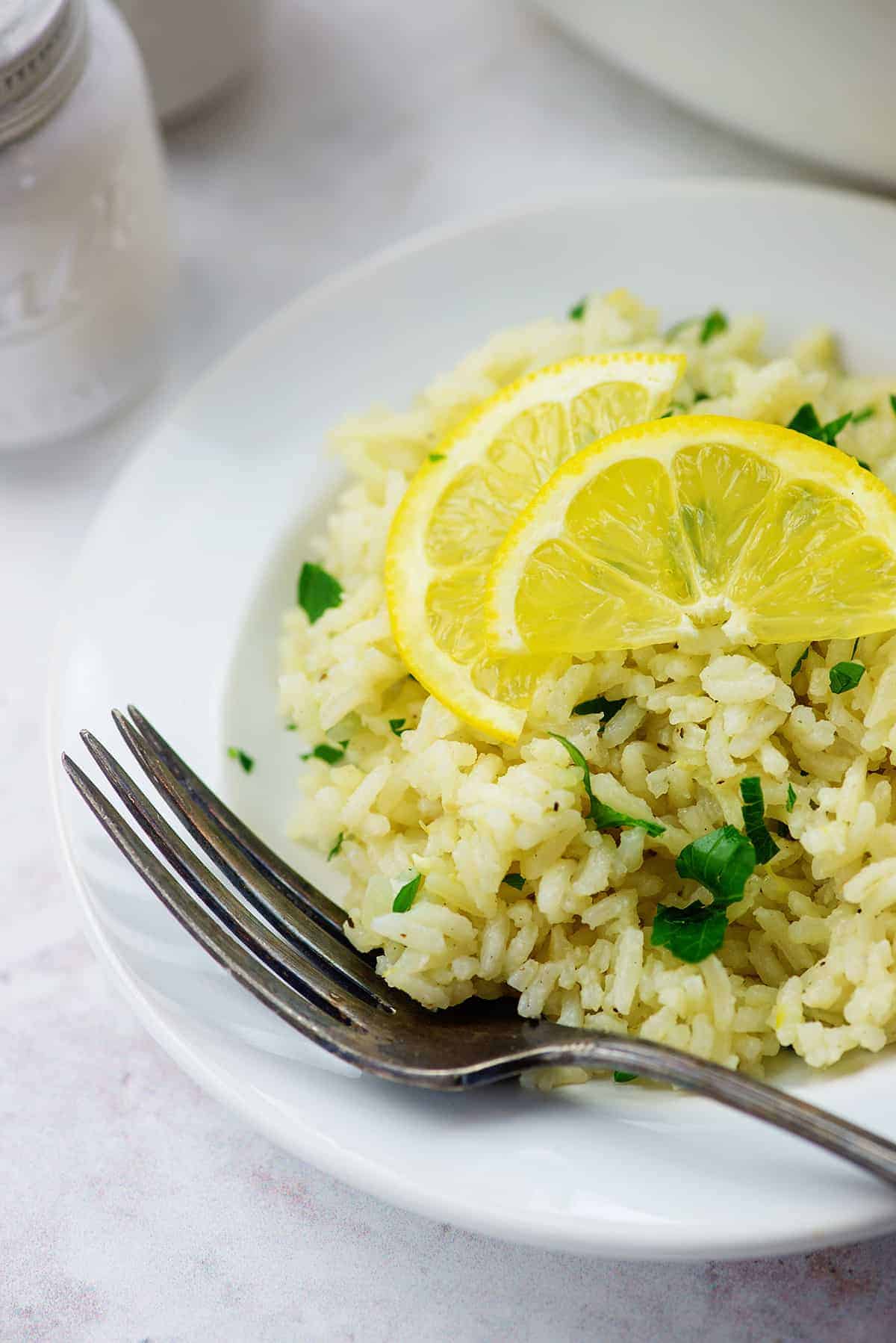 A plate of rice on a table topped with two lemon slices.