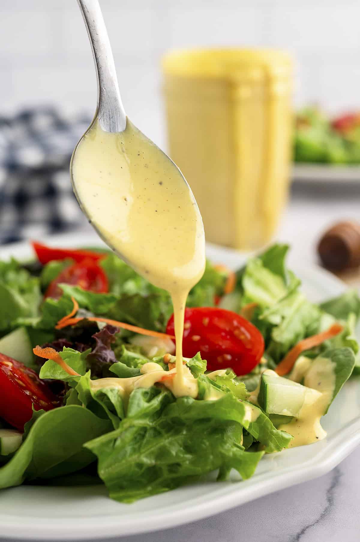 Honey mustard being drizzled over green salad.