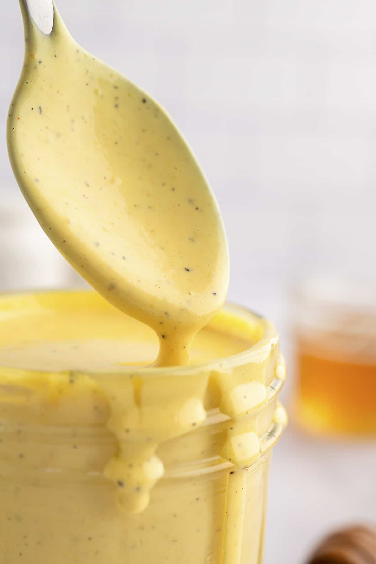 Close up of honey mustard drizzling off a spoon.