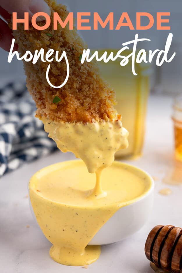 Chicken strip being dipped into honey mustard.