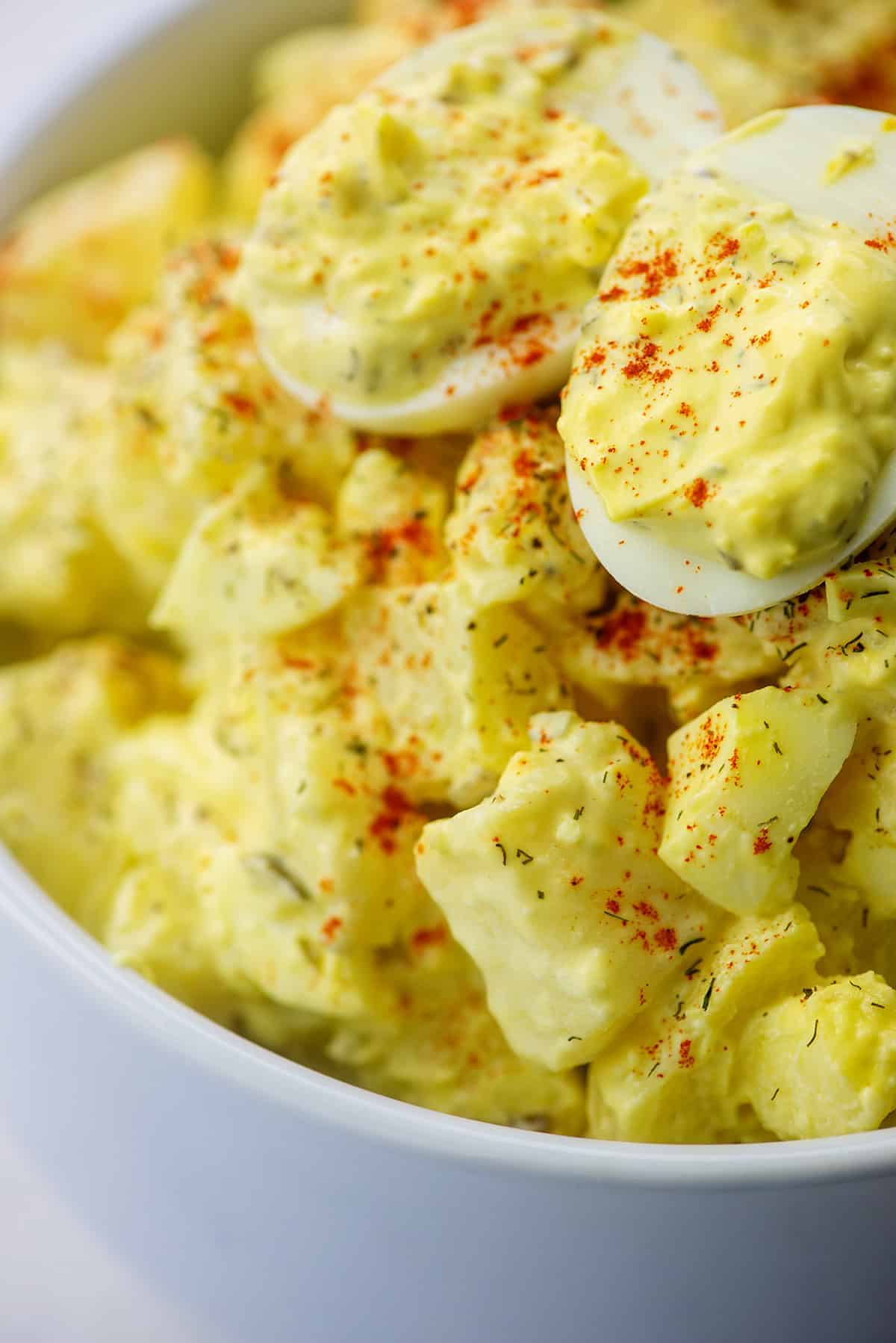potato salad recipe with deviled eggs in white bowl