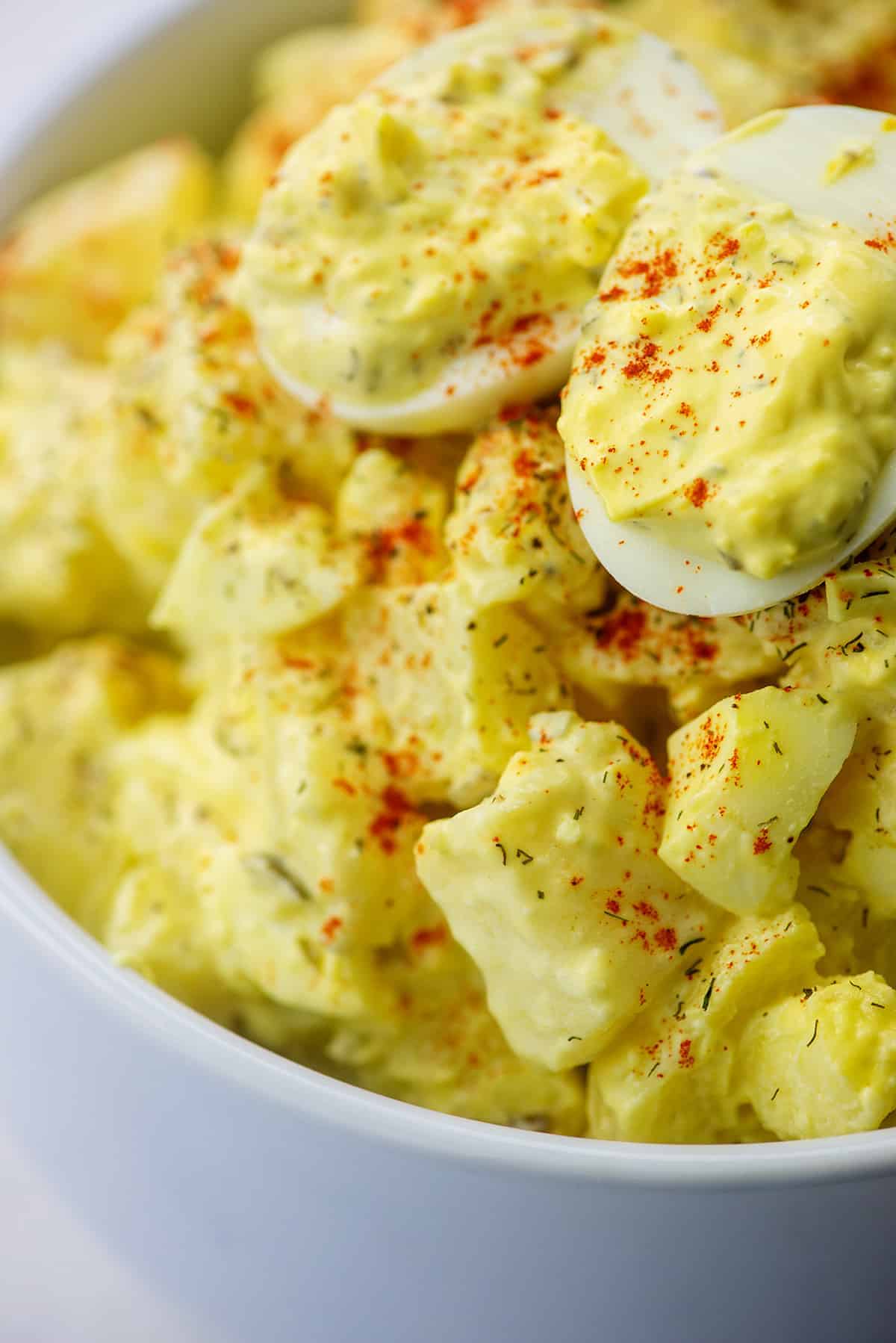 potato salad recipe with deviled eggs in white bowl