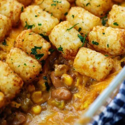cheesy taco tater tot casserole in white baking dish with beans