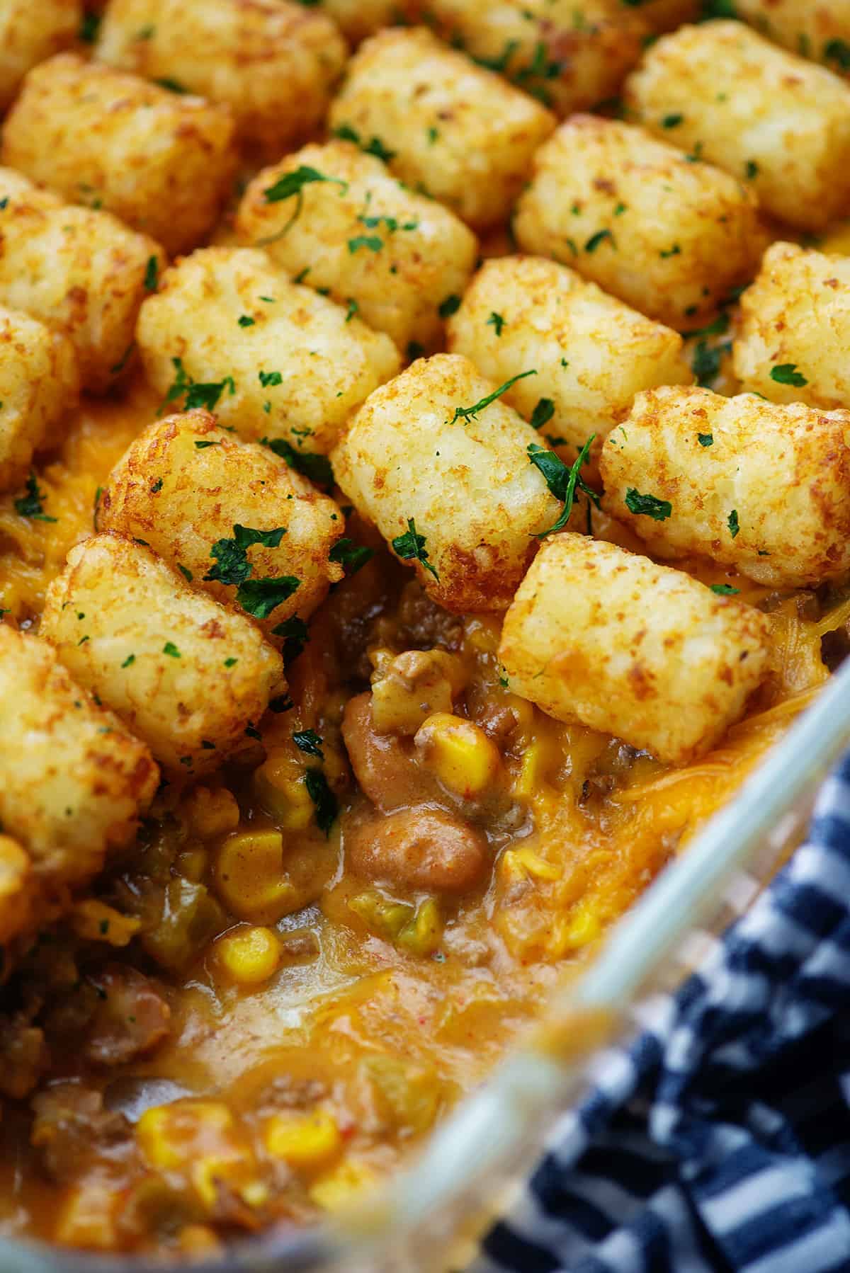 cheesy taco tater tot casserole in white baking dish with beans