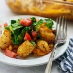 tater tot casserole on white plate with blue napkin