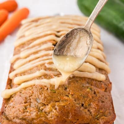 Cream cheese glaze being drizzled over zucchini carrot bread.