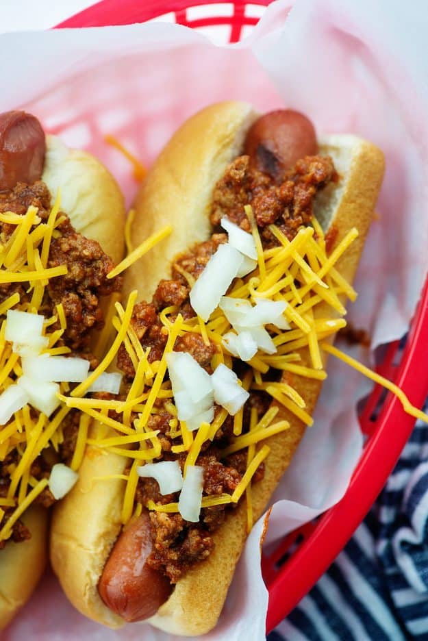 homemade chili dogs in red basket with cheddar and onions