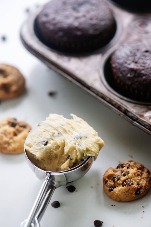 frosting in cookie scoop surrounded by cupcakes and mini cookies