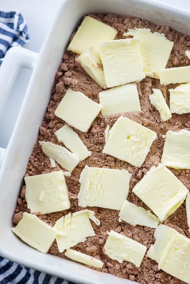 butter slices over chocolate cake mix in white baking dish