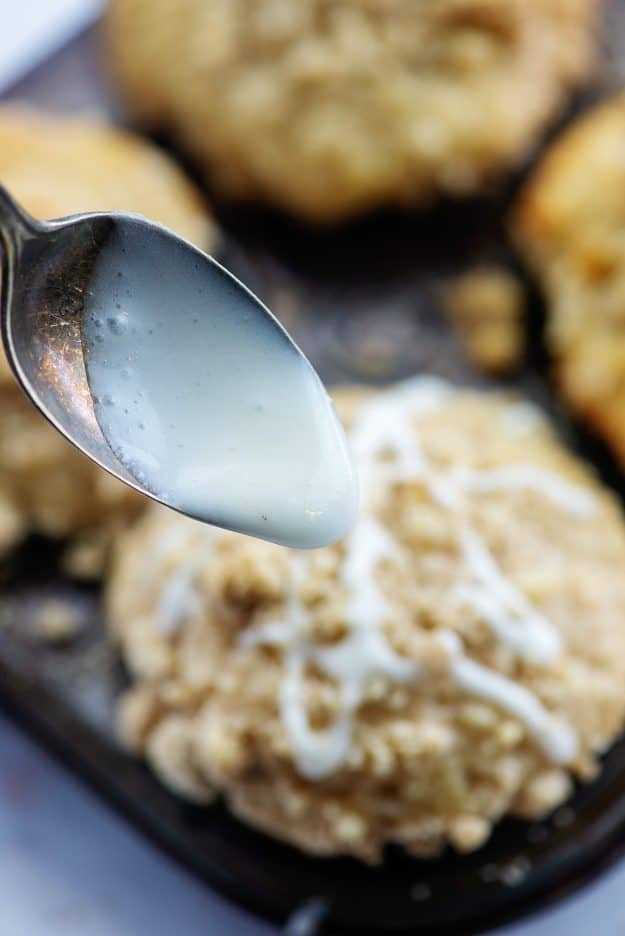 glaze on a spoon being drizzled over muffins