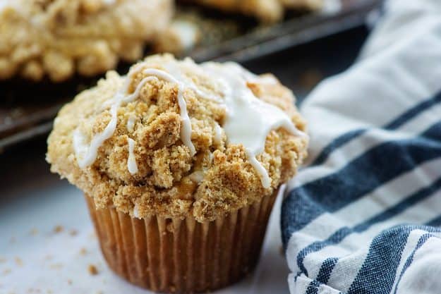 muffin topped with streusel and glaze next to blue striped napkin