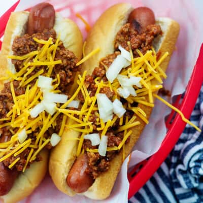 hot dogs in red basket with chili and cheese on top