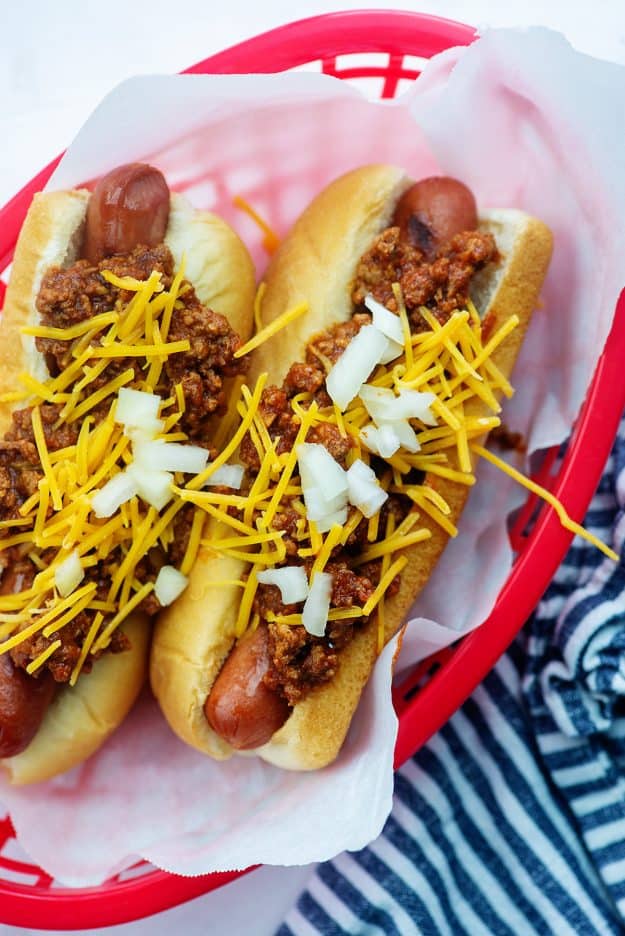 hot dogs in red basket with chili and cheese on top