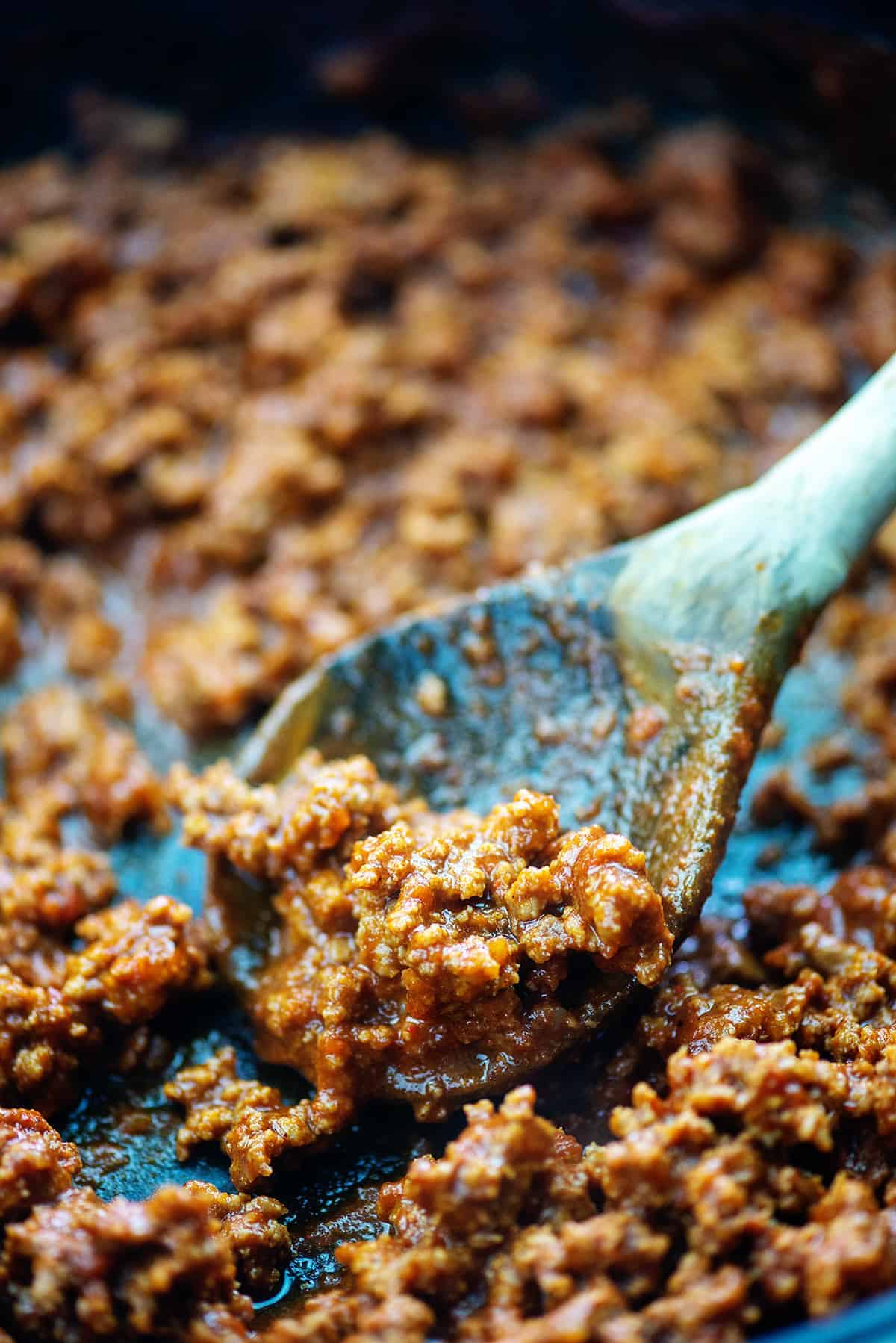 hot dog chili is cast iron skillet with wooden spoon