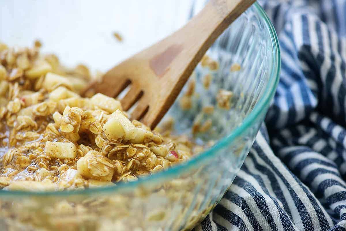 apple and oats in mixing bowl with wooden spoon