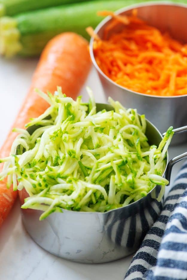 shredded zucchini and carrots in measuring cups