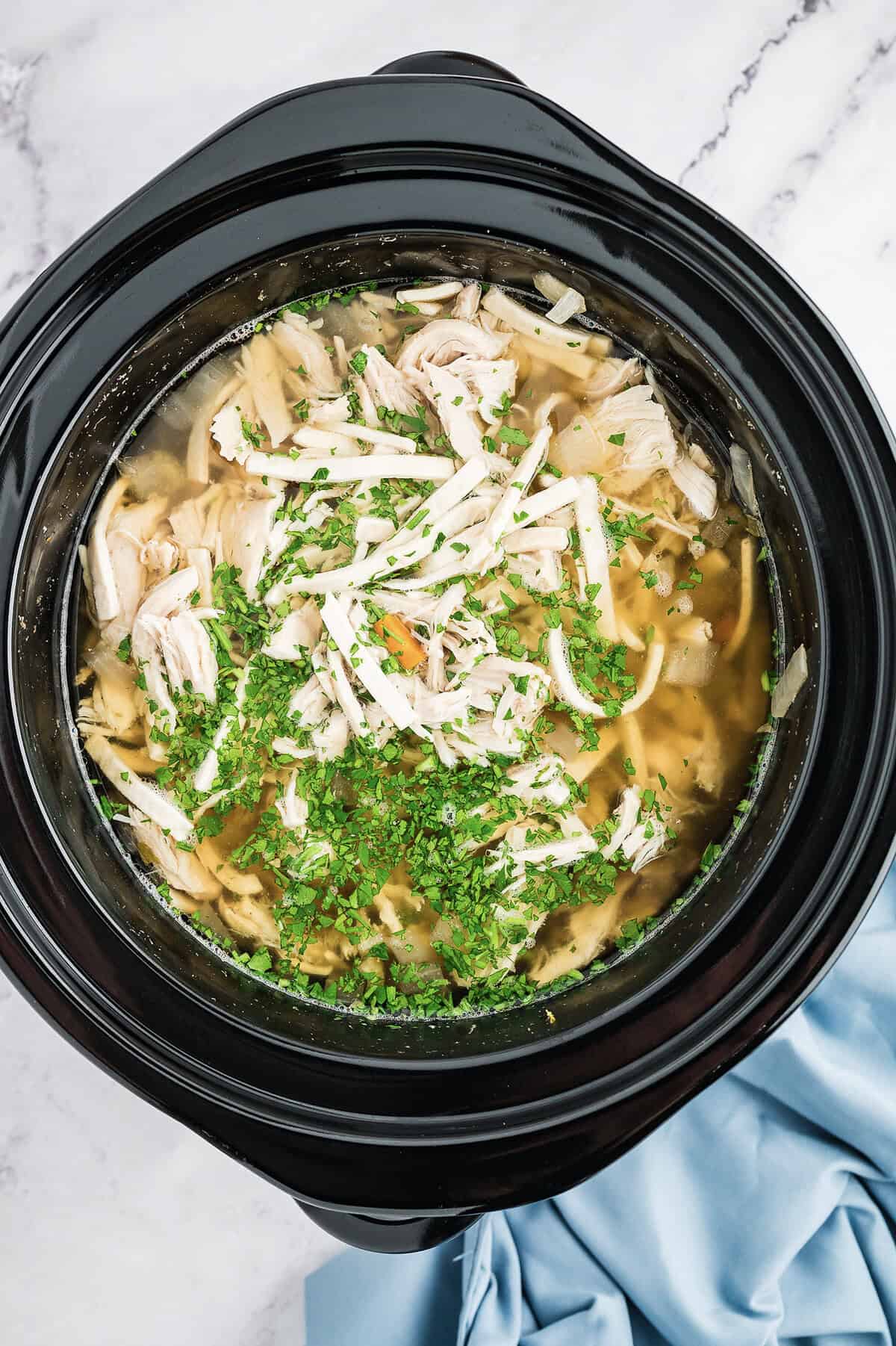 Noodles in crockpot for chicken noodle soup recipe.