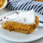 pumpkin pie with chocolate and whipped cream on white plate with blue striped napkin