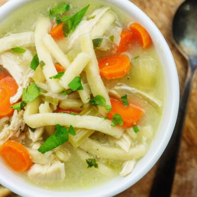 slow cooker chicken noodle soup recipe in white dish surrounded by crackers
