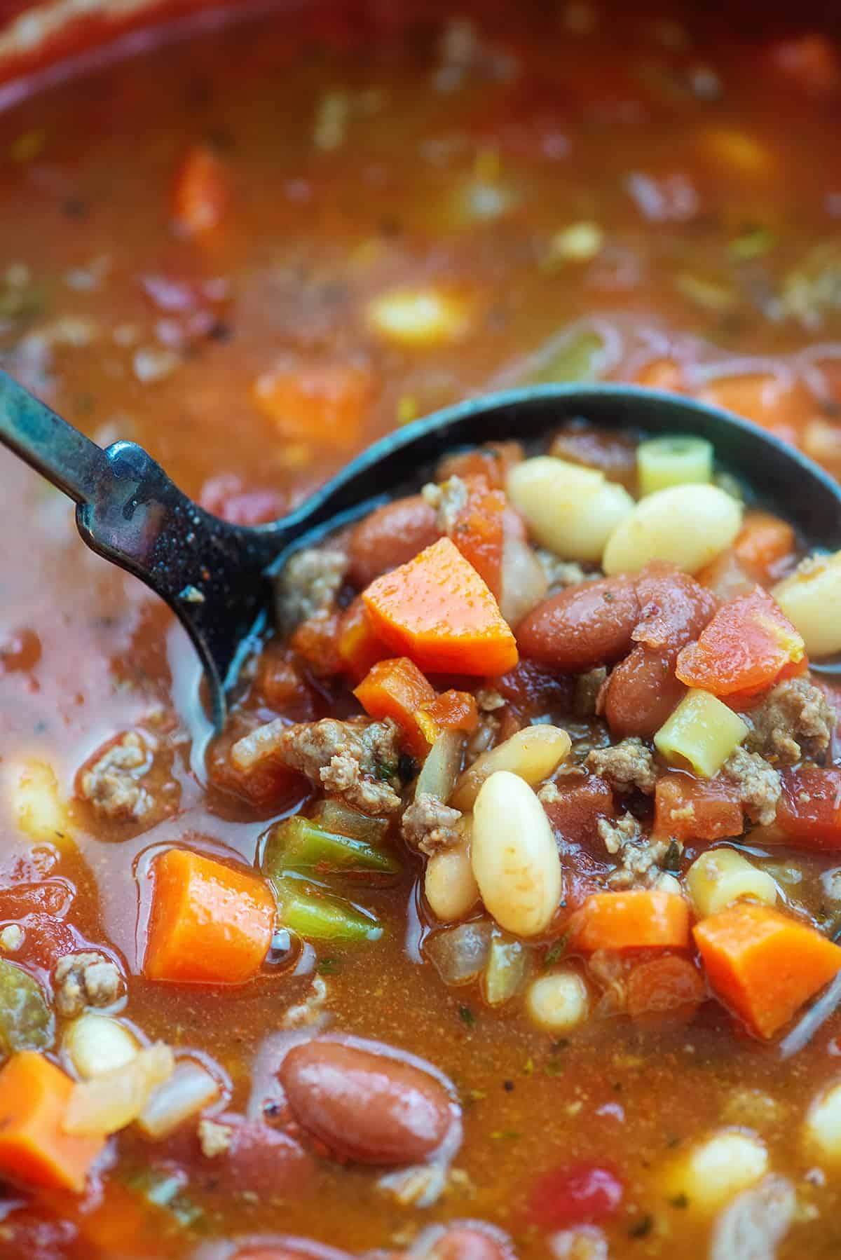 Soup pot with ladle full of pasta fagioli.