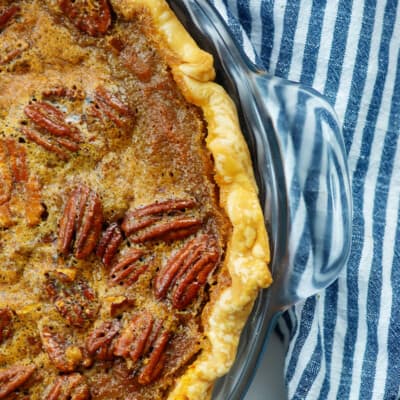 pumpkin pecan pie in glass pie plate with blue striped napkin