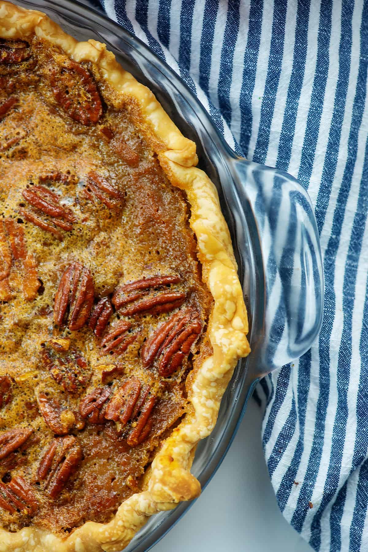 pumpkin pecan pie in glass pie plate with blue striped napkin