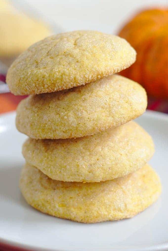 pumpkin sugar cookies stacked on plate.