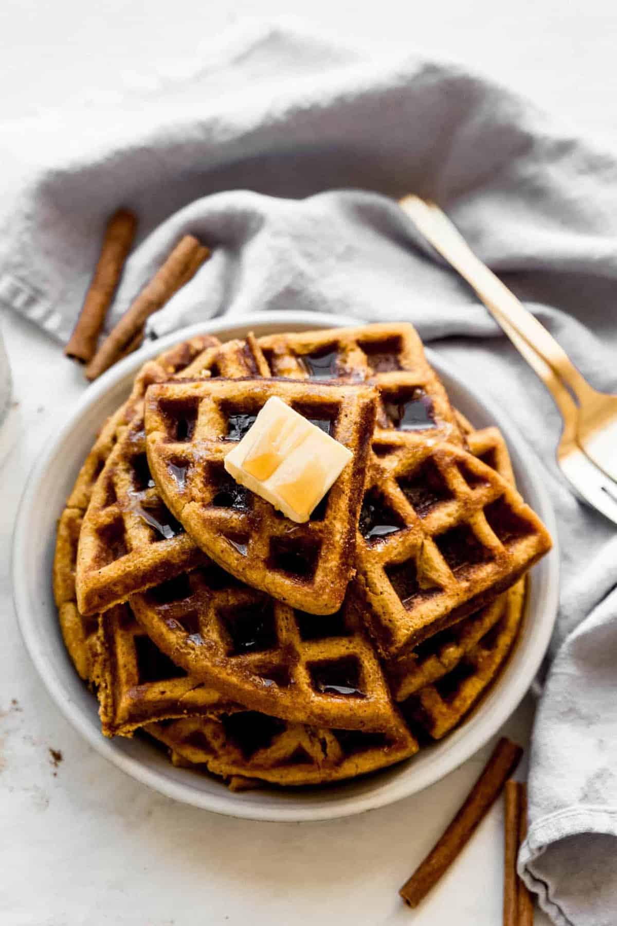 pumpkin waffles in a pile in a white bowl.
