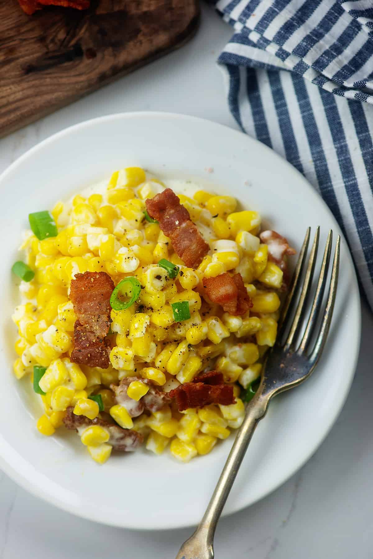 cheesy corn on white plate with fork.