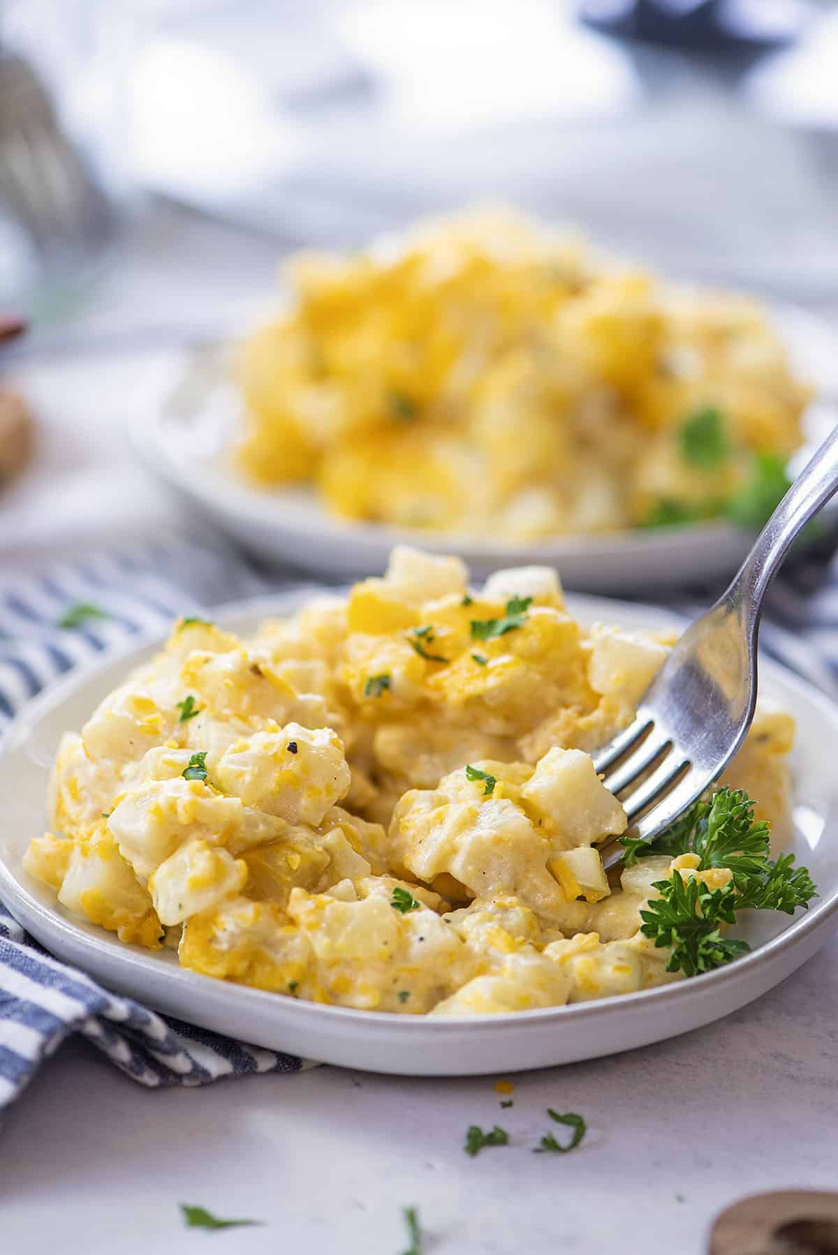 cheesy hashbrown casserole on white plates.