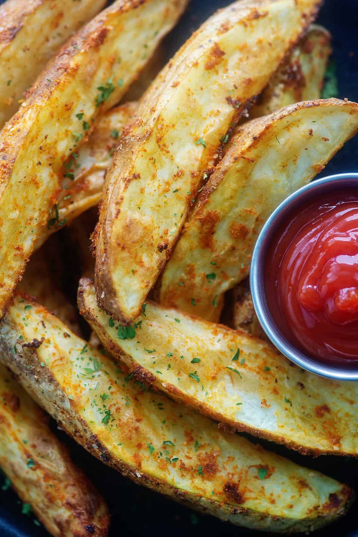 potato wedges on plate with cup of ketchup.