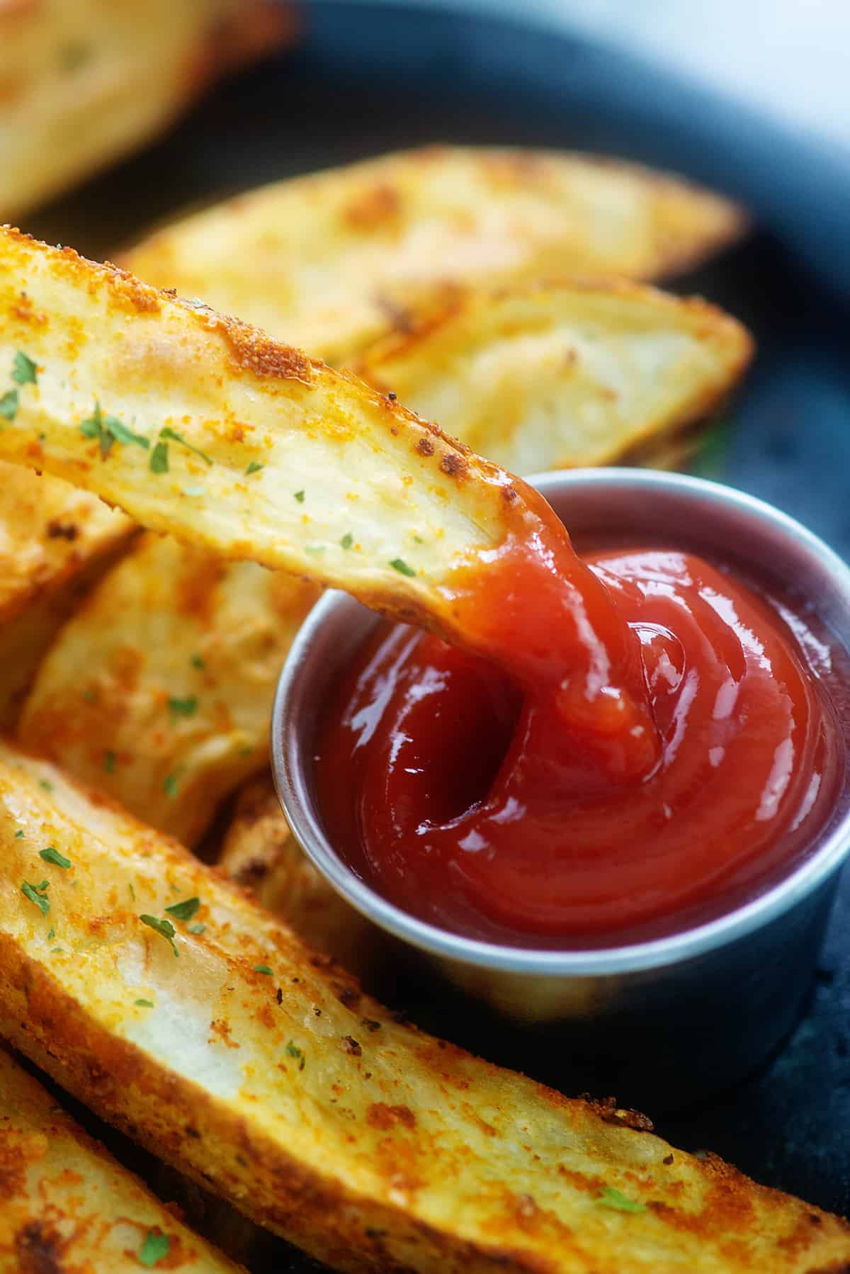 potato wedge being dipped in ketchup.