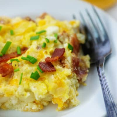 slice of Amish breakfast casserole on white plate with fork.