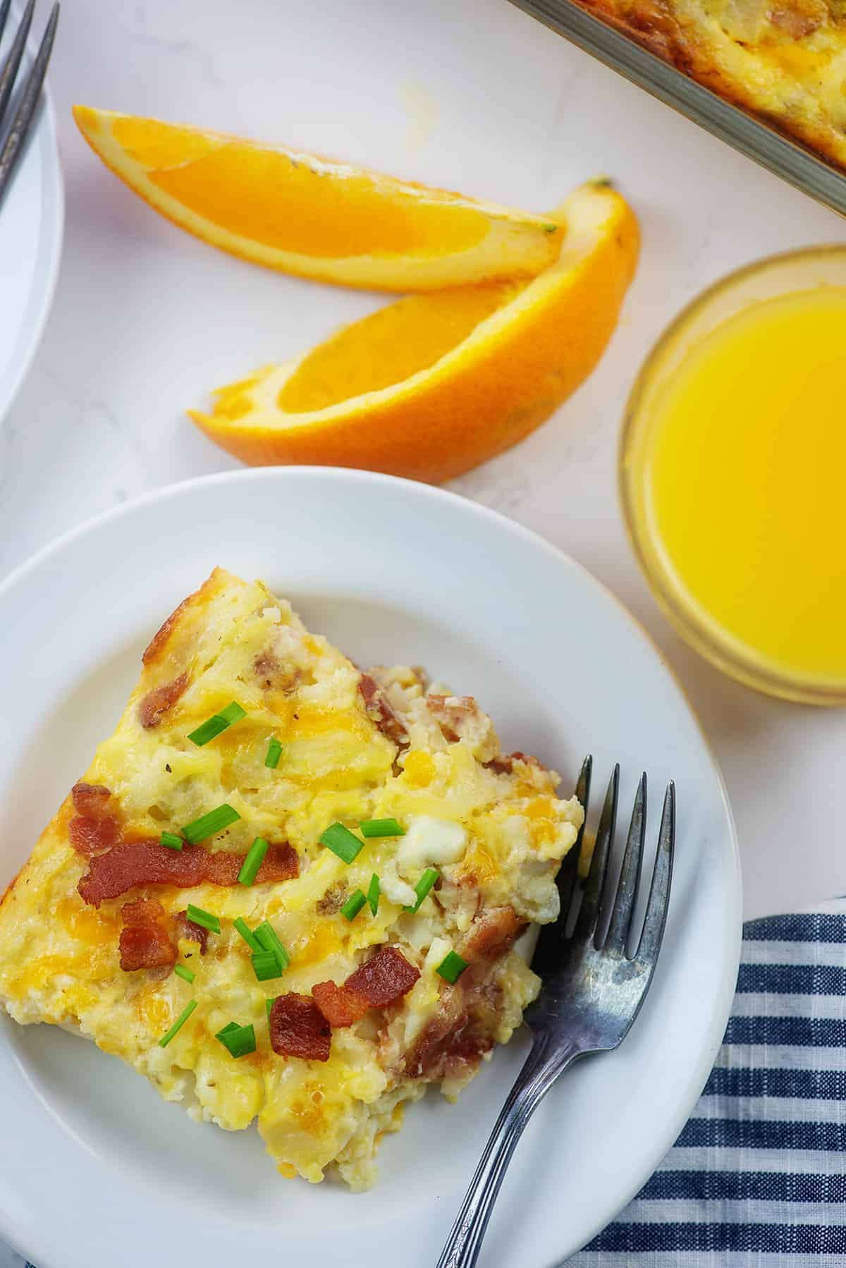 Amish breakfast casserole recipe on white plate with oranges.