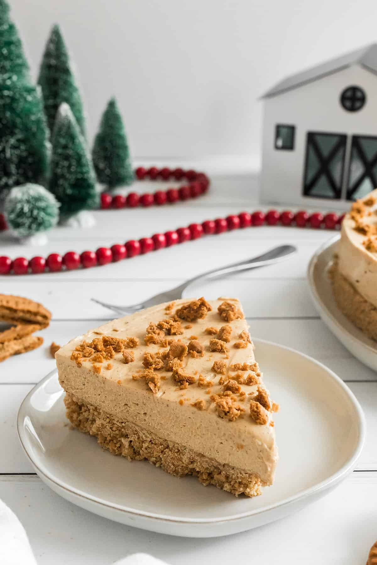 christmas cheesecake on white plate with christmas decor in the background.