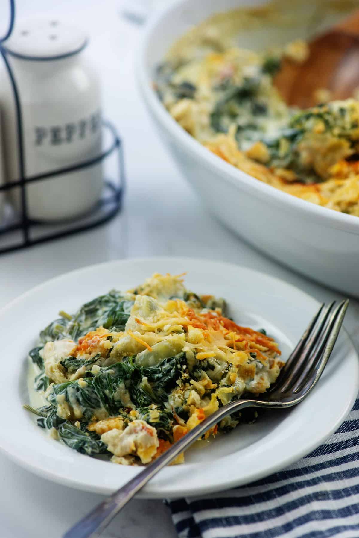 spinach casserole on white plate with vintage fork.
