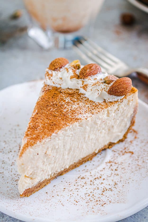 creamy eggnog cheesecake on white plate topped with cinnamon.