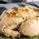 whole chicken cooked in a pressure cooker on a bed of herbs.