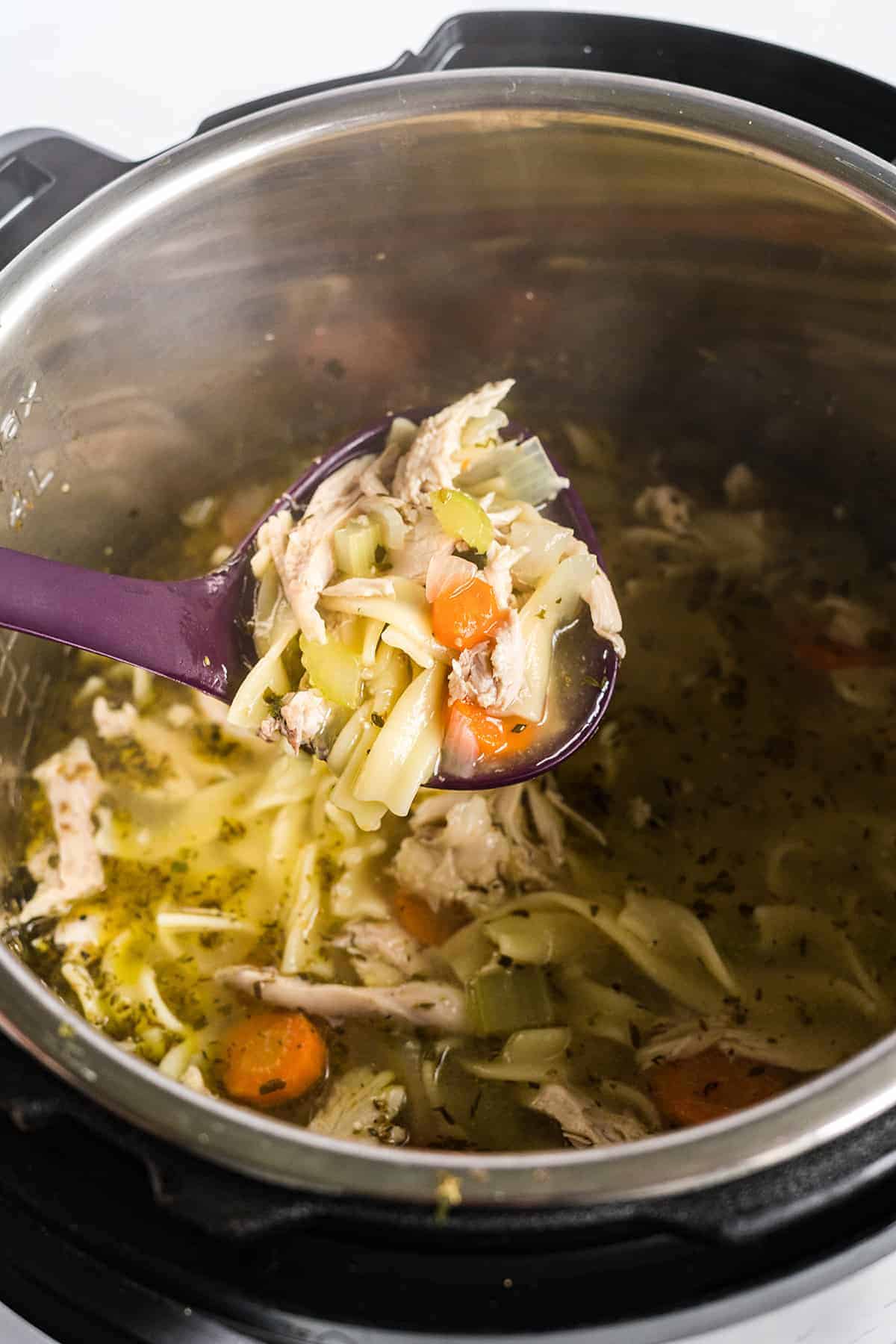 chicken noodle soup being ladled out of the Instant Pot.